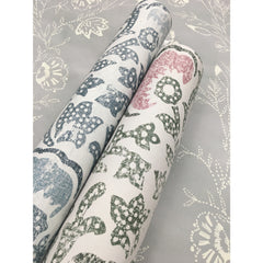 Two rolls of Barbier Wallpaper featuring blue, green, and pink floral patterns resting on a flat sheet of matching gray floral wallpaper.