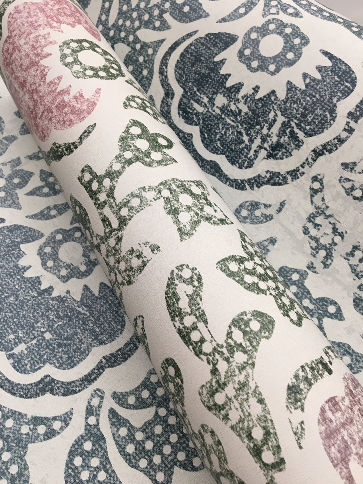 Blaise Wallpaper roll featuring a distressed floral and paisley pattern in shades of pink, green, and blue on a white background.