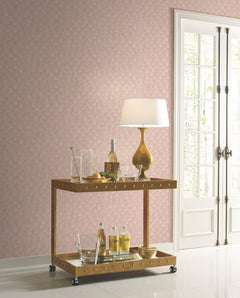 Candice Olson Luminous Gingko Wallpaper in pink with a repeating white gingko leaf pattern on a wall behind a two-tiered gold bar cart.