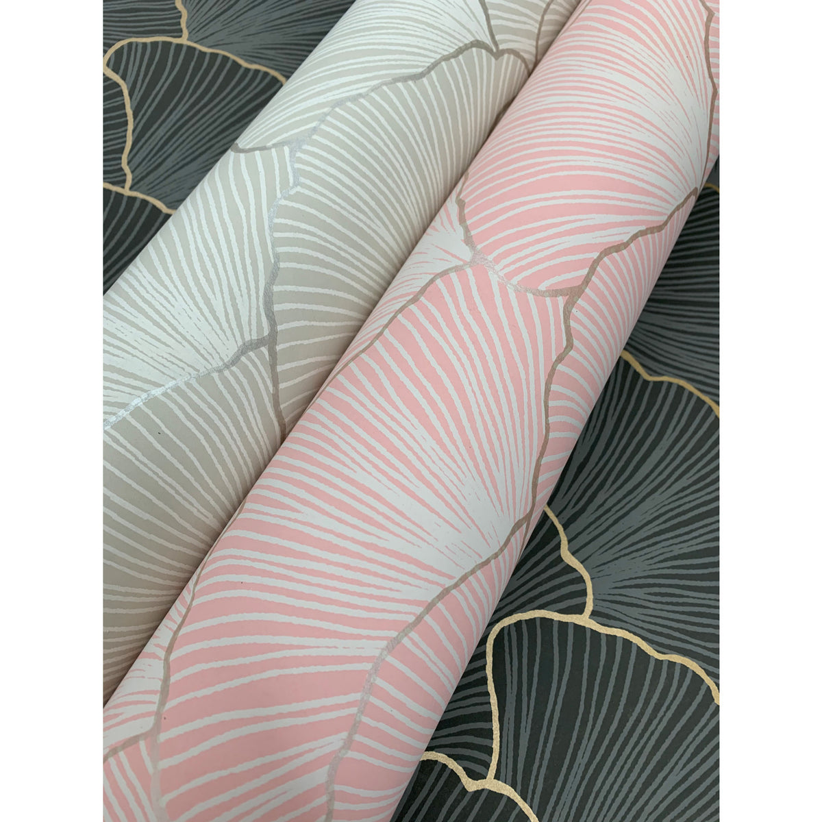 Three rolls of Candice Olson Luminous Gingko Wallpaper in pink, light grey, and charcoal grey, each featuring a gingko leaf pattern with metallic-toned outlines.