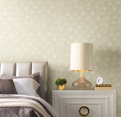 Candice Olson Luminous Ginkgo Wallpaper features a repeating fan-like ginkgo leaf pattern in light tones behind a bedside table with a lamp, small plant, and clock.