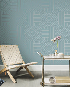 Candice Olson Diverging Diamonds Wallpaper features a blue repeating geometric pattern of interlocking silver diamonds and lines, displayed behind a wooden chair and a metal serving cart.