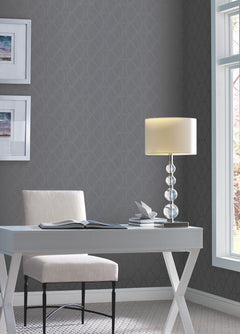 A white desk and chair set against a dark gray Candice Olson Opposites Attract Wallpaper by York Wallcoverings, featuring a repeating geometric leaf pattern.