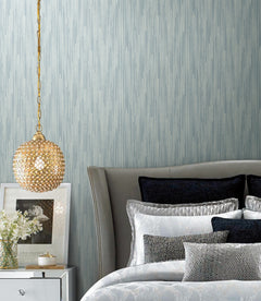 Candice Olson Bargello Wallpaper by York Wallcoverings in light blue with a subtle vertical pinstripe pattern behind a bedroom scene featuring a gold globe pendant light.