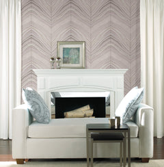 A white sofa sits in front of a fireplace featuring Candice Olson Onyx Strata Wallpaper with a wavy, chevron-style pattern in shades of grey and pink.