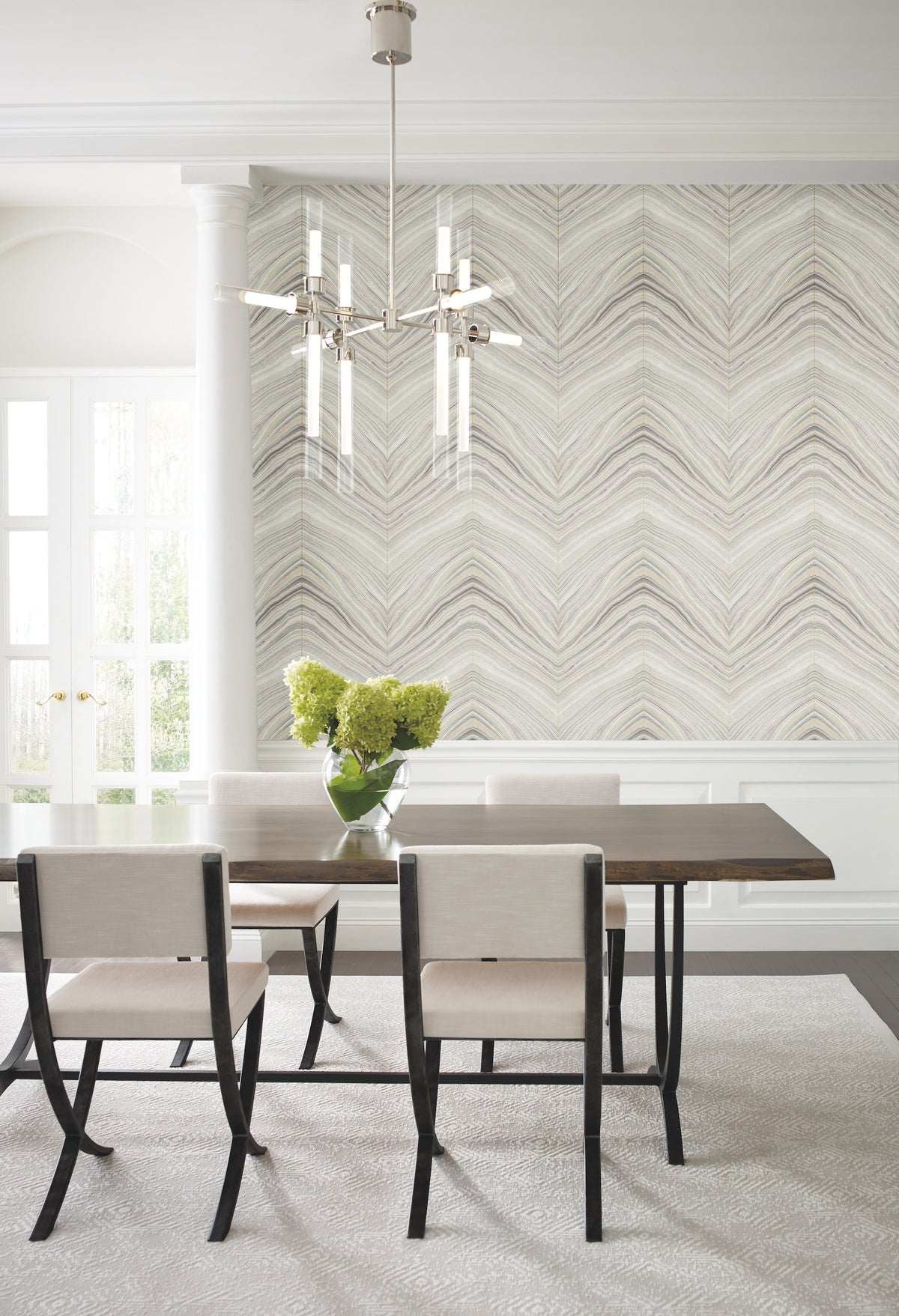 A dining room featuring Candice Olson Onyx Strata Wallpaper with a beige and grey chevron pattern, a dark wood table with upholstered chairs, and a glass vase with greenery.