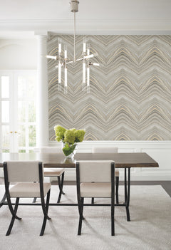 Dining room with a dining table, four chairs, and a wall featuring Candice Olson Onyx Strata Wallpaper by York Wallcoverings in a repeating wavy chevron pattern of gray, beige, and gold.