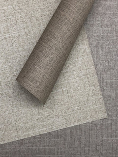 Stacked rolls of Candice Olson Errandi Wallpaper by York Wallcoverings featuring a neutral, fabric-like textured pattern in shades of beige and gray.