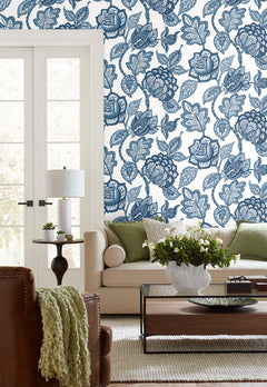 Midsummer Jacobean Wallpaper featuring a blue and white botanical print of large flowers and leaves on a living room wall.