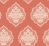The Signet Medallion Damask Wallpaper by York Wallcoverings features an elegant, vintage-inspired design with ornate white floral motifs arranged in a seamless pattern over a muted coral background.