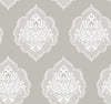 Signet Medallion Damask Wallpaper by York Wallcoverings features a repeating ornate white medallion damask pattern with floral and swirl details set against a muted gray background. This symmetrical, vintage-inspired design creates a classic and elegant wallpaper look.