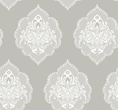 Signet Medallion Damask Wallpaper by York Wallcoverings features a repeating ornate white medallion damask pattern with floral and swirl details set against a muted gray background. This symmetrical, vintage-inspired design creates a classic and elegant wallpaper look.