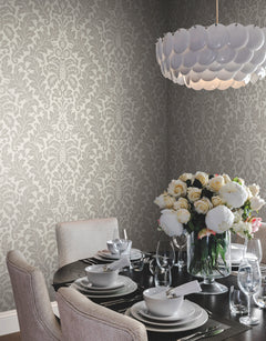 Dining room corner featuring light gray Candice Olson Modern Romance Wallpaper, a dark round table set for dinner, and a large vase of white peonies.