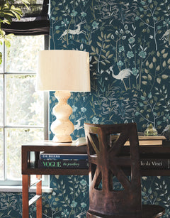 Ronald Redding Aspen Wallpaper in dark teal featuring a repeating pattern of white deer, herons, and stylized foliage.