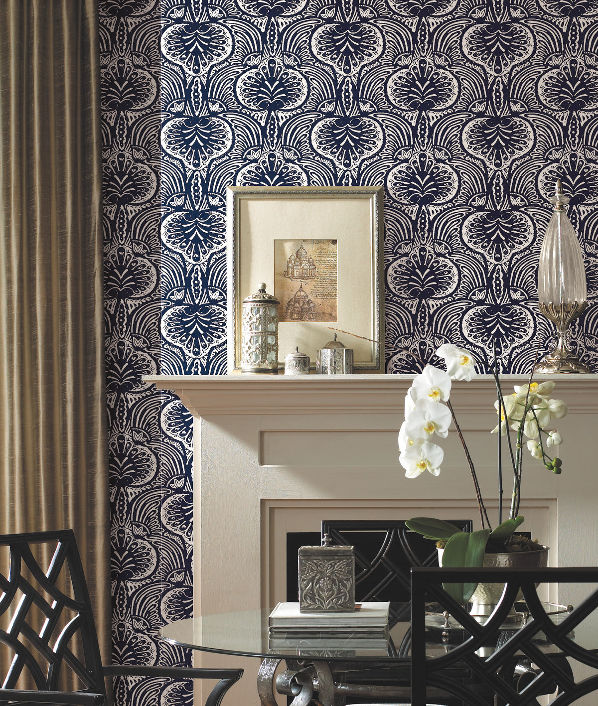 Ronald Redding Lotus Palm wallpaper with a repeating navy blue and white pattern of stylized palm-like leaves behind a fireplace mantel decorated with framed art, decorative containers, and an orchid.