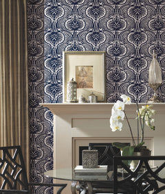 Ronald Redding Lotus Palm wallpaper with a repeating navy blue and white pattern of stylized palm-like leaves behind a fireplace mantel decorated with framed art, decorative containers, and an orchid.