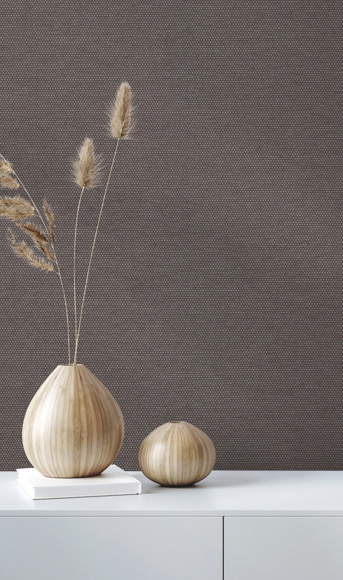Two wooden vases with dried grass on a white surface are set against a backdrop of QuietWall Varna Wallpaper by York Wallcoverings, creating a minimalist and natural decor setting.