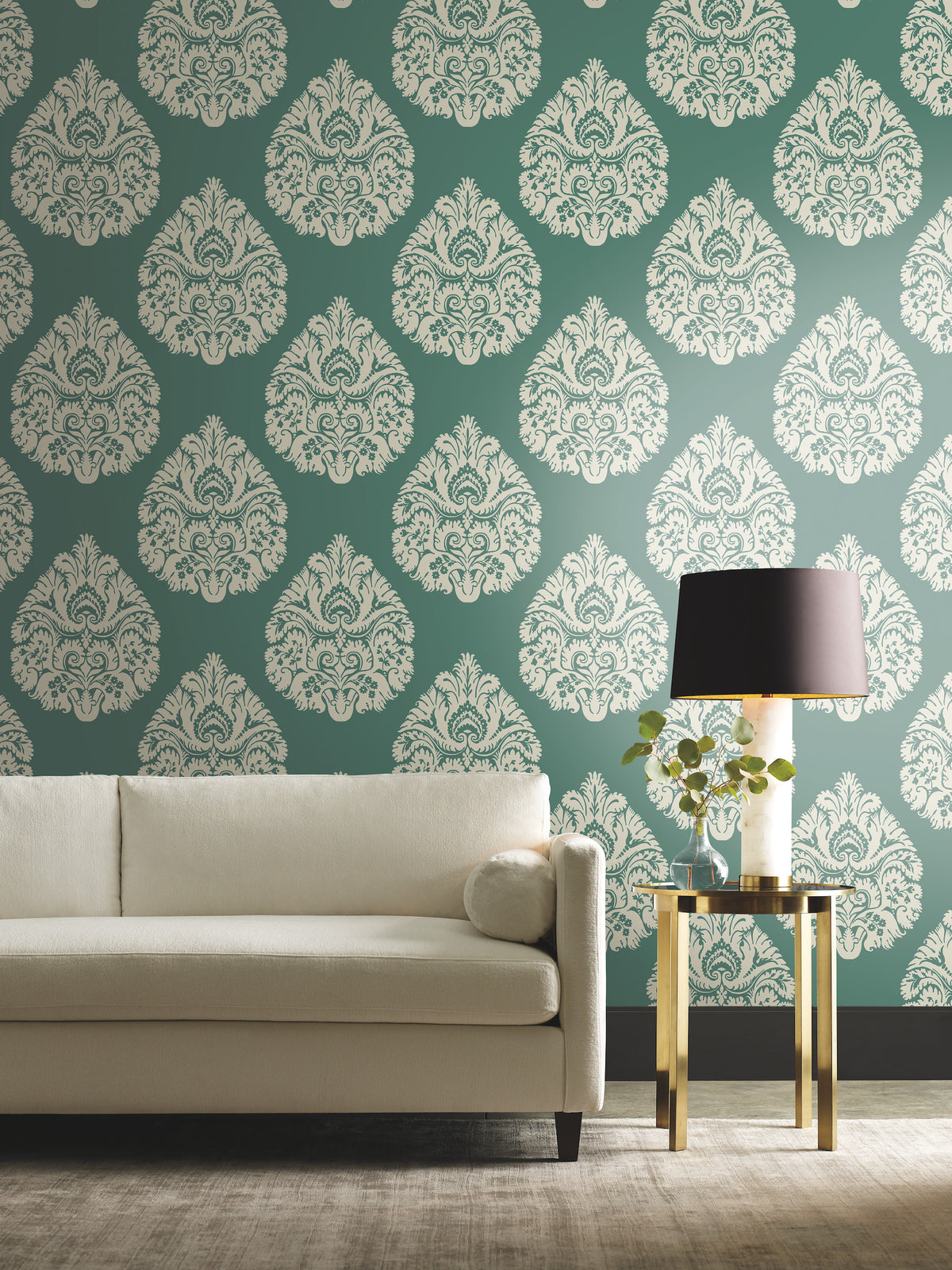 Ronald Redding Teardrop Damask Wallpaper featuring a repeating white teardrop-shaped pattern on a dark green background, displayed behind a white sofa and a side table with a lamp.
