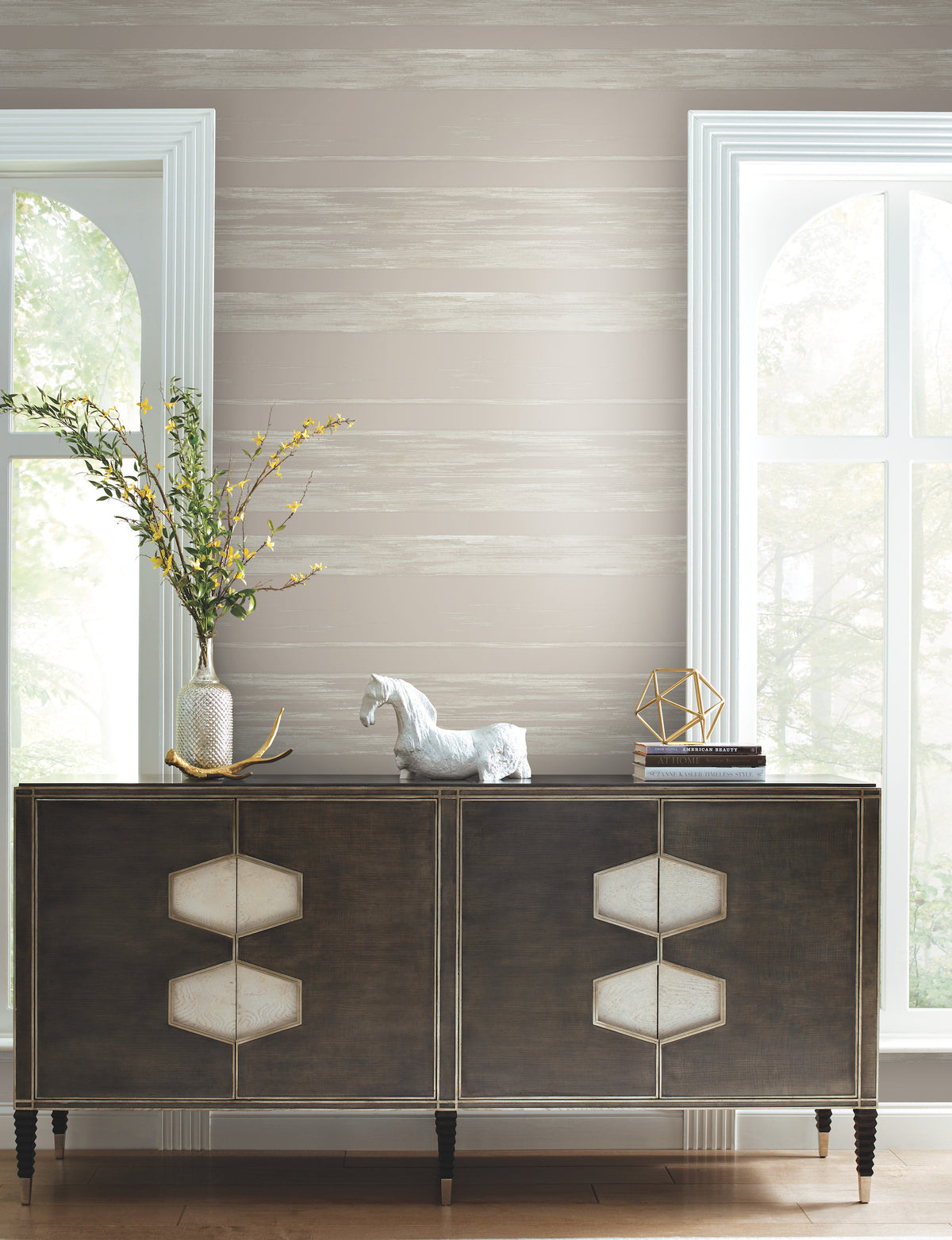Ronald Redding Horizontal Dry Brush Wallpaper featuring horizontal, dry-brushed stripes in shades of gray and white behind a dark wood cabinet.