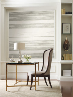 Ronald Redding Horizontal Dry Brush Wallpaper by York Wallcoverings featuring soft, horizontal grey and white stripes with a textured, dry-brush effect installed on an accent wall behind a writing desk.