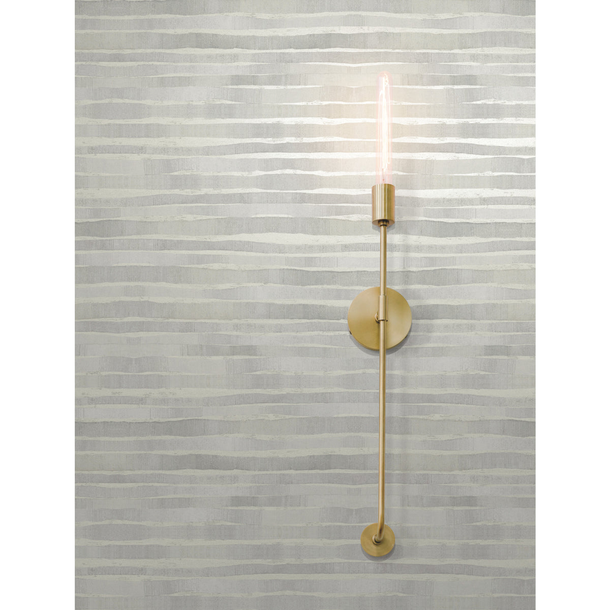 A modern gold-toned wall sconce with an exposed filament bulb mounted on Ronald Redding Dreamscapes Wallpaper featuring horizontal, textured grey and white brushstroke stripes.