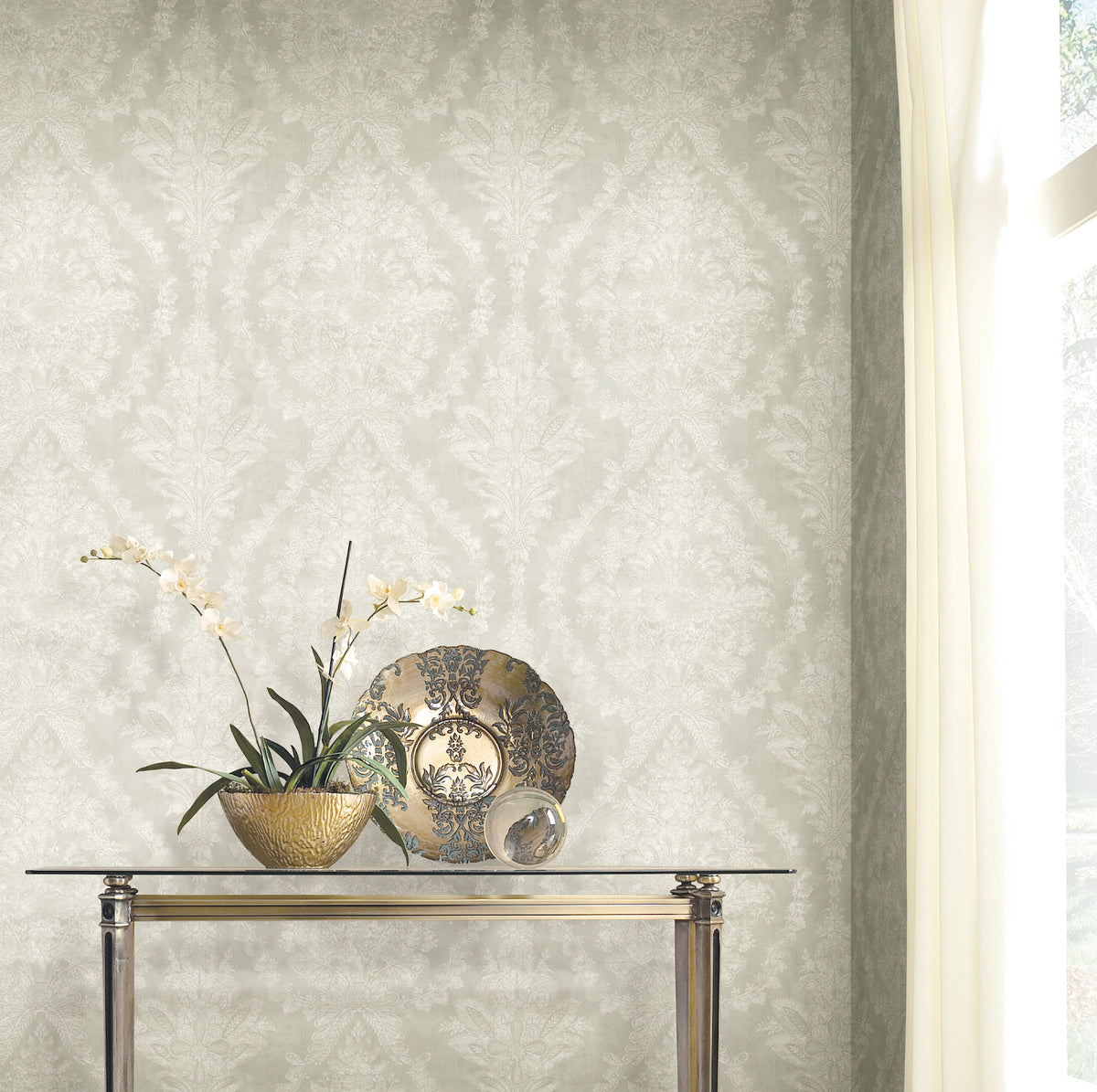 Ronald Redding Charleston Damask Wallpaper in light gray with a white floral pattern, displayed behind a glass console table featuring an orchid and a decorative plate.