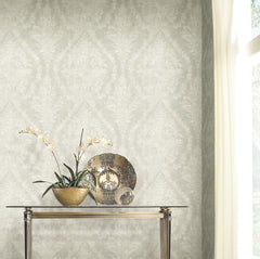 Ronald Redding Charleston Damask Wallpaper in light gray with a white floral pattern, displayed behind a glass console table featuring an orchid and a decorative plate.