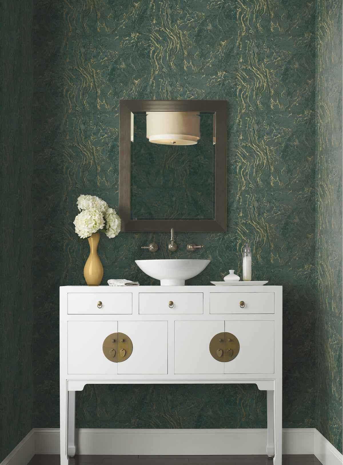 A white bathroom vanity with a bowl sink and a rectangular mirror against a wall covered in green and gold Ronald Redding Polished Marble Wallpaper.