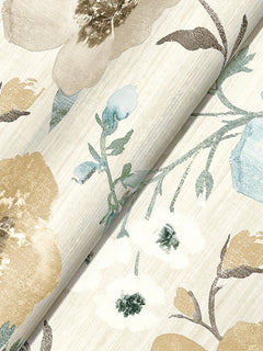 A close-up of York Wallcoverings’ Evelyn Floral Wallpaper, showcasing a floral pattern in beige, blue, and white with green stems and leaves on a light textured background. The wallpaper is partially rolled.