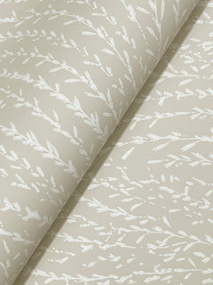 Experience the Willow Song Botanical Wallpaper by York Wallcoverings—beige paper adorned with a subtle white pattern of delicate leaves and branches, partially rolled to showcase its texture and refined design.