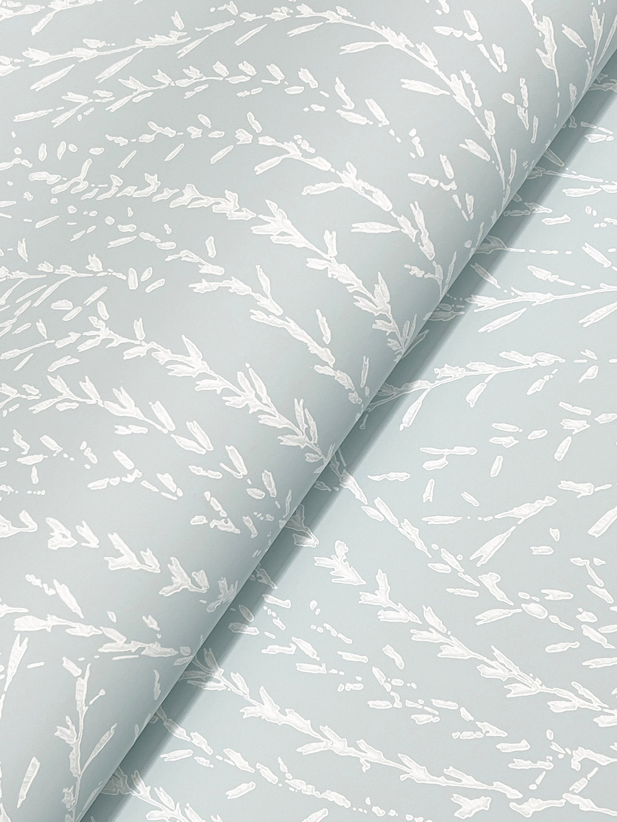 Close-up of Willow Song Botanical Wallpaper by York Wallcoverings, featuring a delicate white botanical pattern of leafy branches on a light blue background. The wallpaper is slightly folded, highlighting its repeating nature-inspired design.