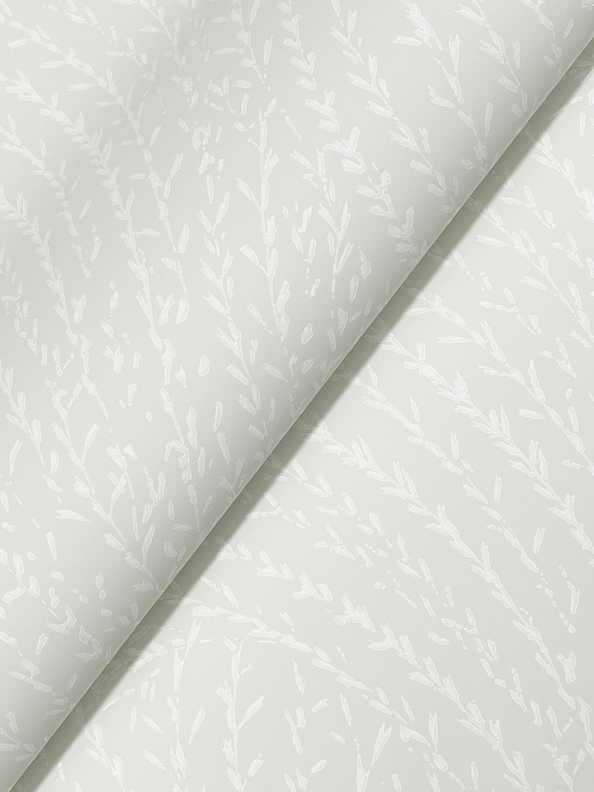 Two sheets of York Wallcoverings’ Willow Song Botanical Wallpaper in pale gray, featuring a subtle white leafy branch motif, overlap diagonally. The minimal botanical design offers a soft and elegant look, making it perfect for decorative accents or wrapping applications.