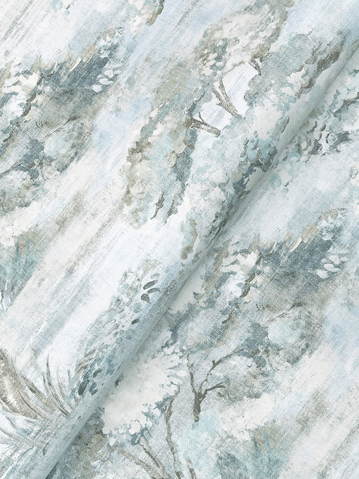 The Moreno Woodland Wallpaper by York Wallcoverings features a pale background adorned with a soft, watercolor-style print of trees and foliage in muted shades of green, gray, and blue, creating a serene, nature-inspired pattern.