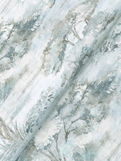 The Moreno Woodland Wallpaper by York Wallcoverings features a pale background adorned with a soft, watercolor-style print of trees and foliage in muted shades of green, gray, and blue, creating a serene, nature-inspired pattern.