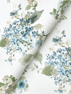 Veiled Garden Floral Wallpaper by York Wallcoverings features a white background adorned with a watercolor-style floral pattern in shades of blue, green, and beige. Delicate flowers and leaves form a soft, elegant design across the wallpaper.