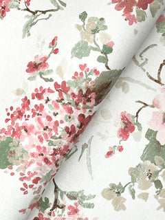 Veiled Garden Floral Wallpaper by York Wallcoverings features watercolor-like pink, red, green, and beige flowers and leaves on a white background, shown slightly folded.