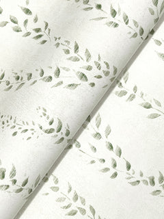 Alpenrose Vine Wallpaper by York Wallcoverings features a white background adorned with a subtle, repeating pattern of green leafy branches. The wallpaper is gently draped, creating a graceful diagonal line across the image and showcasing its soft, slightly textured finish.