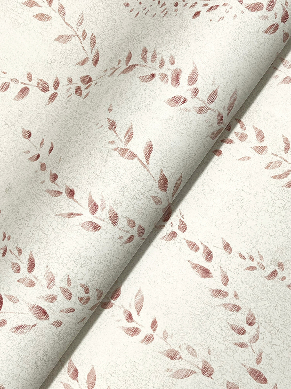 Close-up of Alpenrose Vine Wallpaper by York Wallcoverings, featuring a light-colored background with a subtle crackle texture and a repeating pattern of pinkish-red leafy wreaths. The wallpaper is partially rolled, highlighting its flexible material.