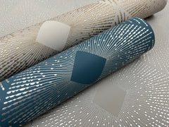 Two rolls of Harlowe Wallpaper by York Wallcoverings—one in teal with silver lines and the other in beige with gold lines—each featuring a geometric sunburst pattern centered around a diamond shape.