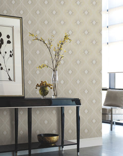 A modern room featuring Harlowe Wallpaper by York Wallcoverings, a black table displaying two vases with yellow flowers, a bowl, and framed leaf artwork. A light chair and tall windows appear in the background.