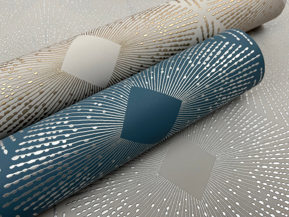 Two rolls of Harlowe Wallpaper by York Wallcoverings, one in teal and one in beige, featuring metallic radiating dotted lines and diamond motifs, displayed on a coordinating patterned background.