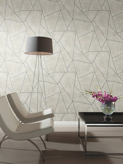 Two modern white chairs, a tall floor lamp, and a black coffee table with a vase of purple flowers sit in front of Nazca Wallpaper by York Wallcoverings in a minimalist room.