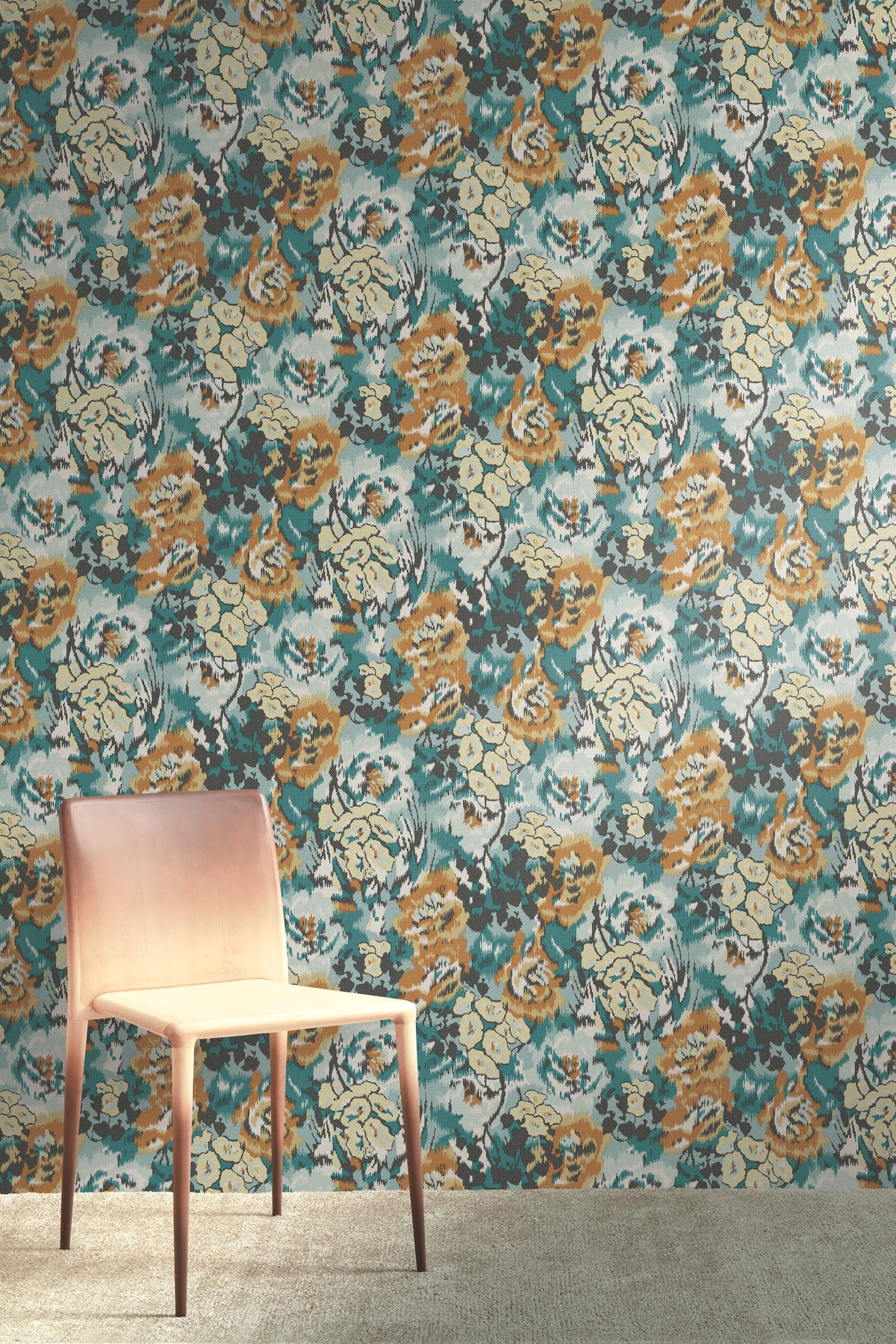A light wooden chair stands on a beige carpet in front of a wall covered in York Wallcoverings’ Flower Pot Wallpaper, featuring colorful, abstract floral patterns in shades of blue, yellow, gray, and white.