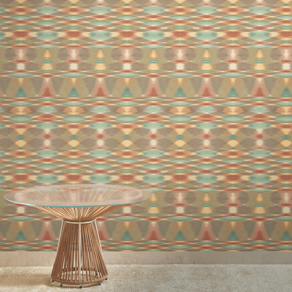 A round, glass-topped table with a wire base stands on a beige carpet in front of the York Wallcoverings Sunrise Flame Wallpaper.