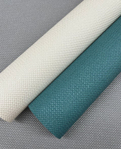Two rolls of Chevronette Wallpaper by York Wallcoverings, in cream and teal, are placed diagonally on a gray Chevronette Wallpaper background. All wallpapers feature a subtle, repeating chevron pattern.