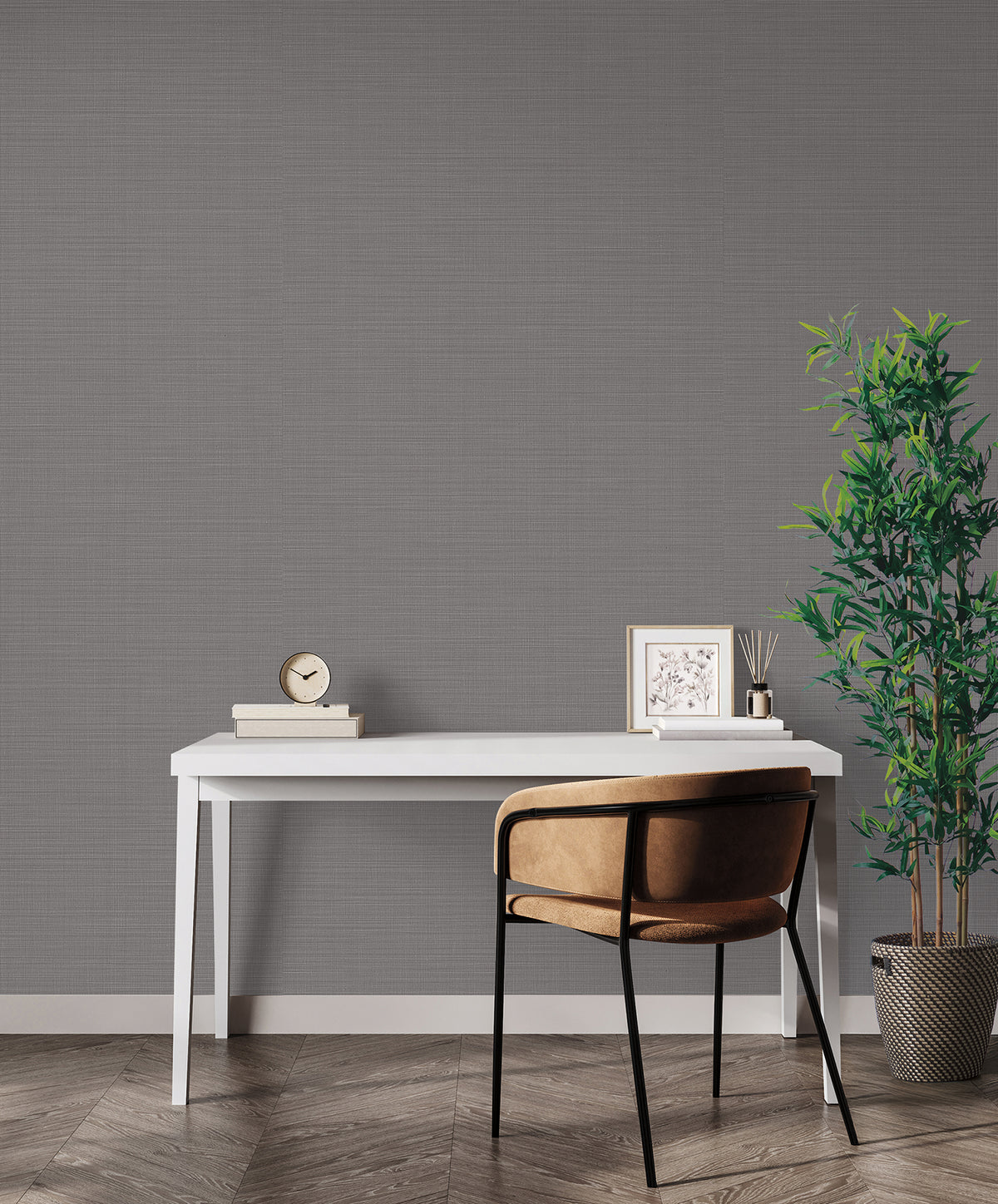 A white desk and brown chair placed against a wall featuring dark gray textured Magnolia Home Meadowbrook Wallpaper.