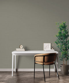 Textured sage green Magnolia Home Meadowbrook Wallpaper on a wall behind a white desk with a chair, a small clock, a framed print, and a potted plant.