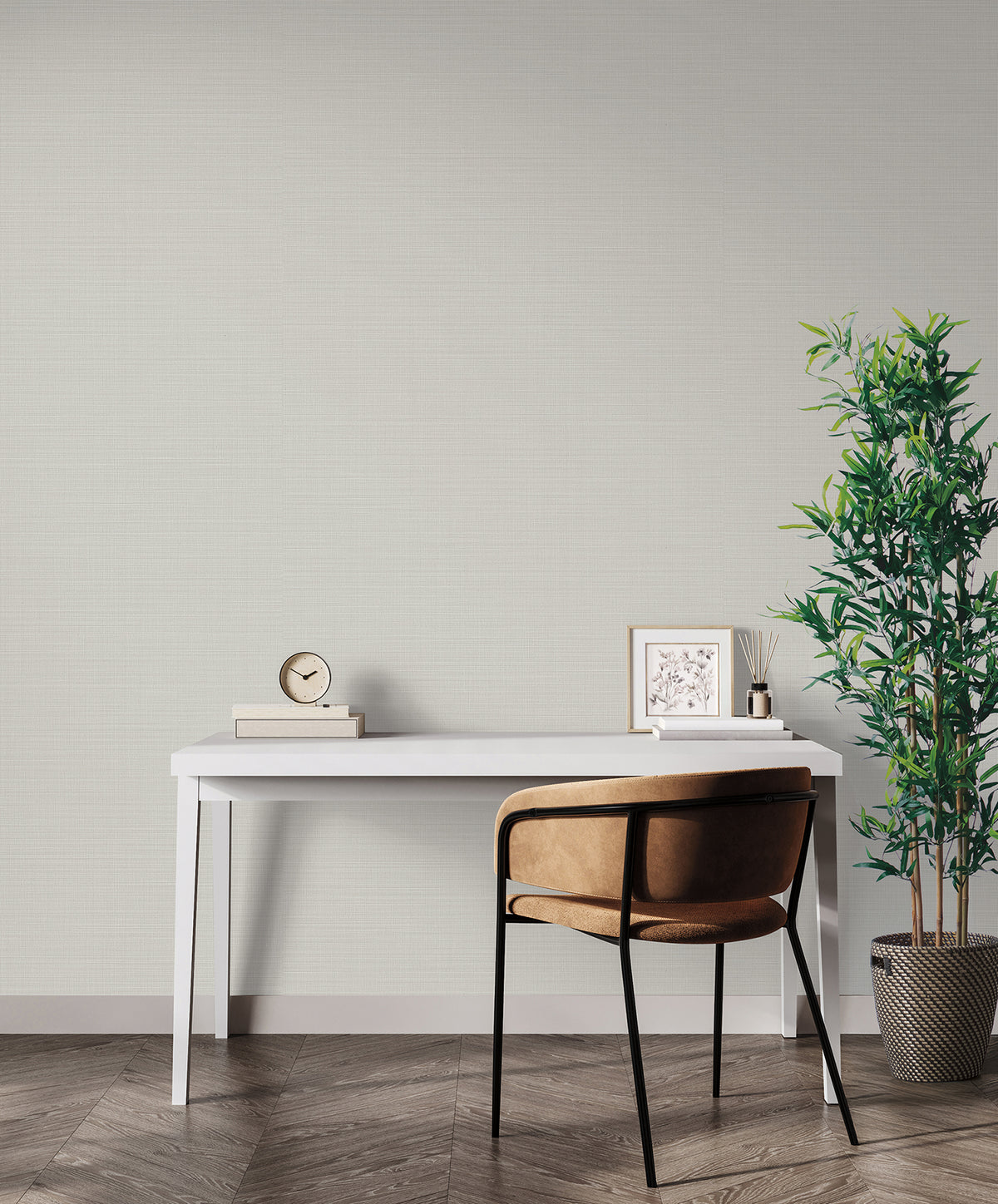 A desk with a clock, framed picture, and chair sits in front of a wall covered in light gray textured Magnolia Home Meadowbrook Wallpaper.