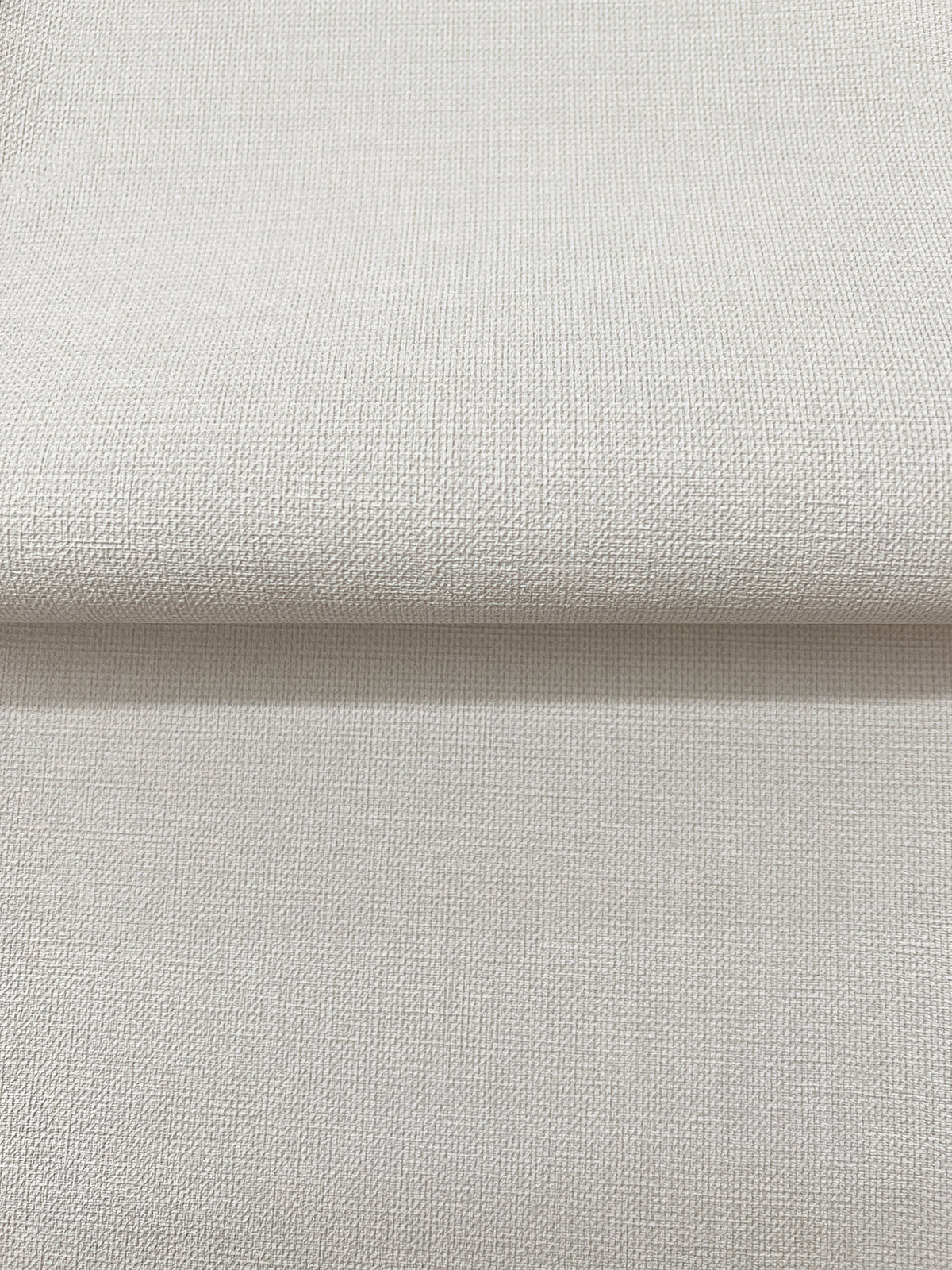 Magnolia Home Meadowbrook Wallpaper in light gray with a subtle, fine-grained texture, shown partially unrolled.