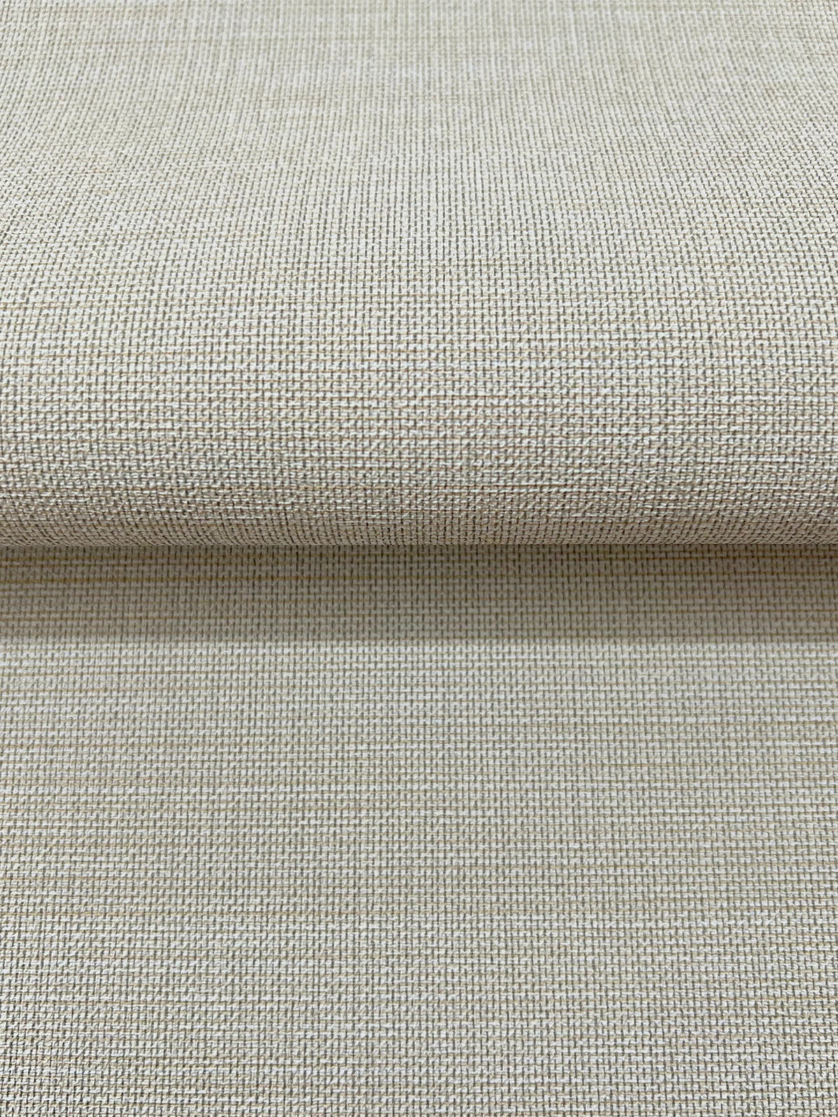 A roll of Magnolia Home Meadowbrook Wallpaper with a beige, woven fabric texture.
